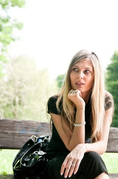 Portrait of young beautiful woman siting on bench in park