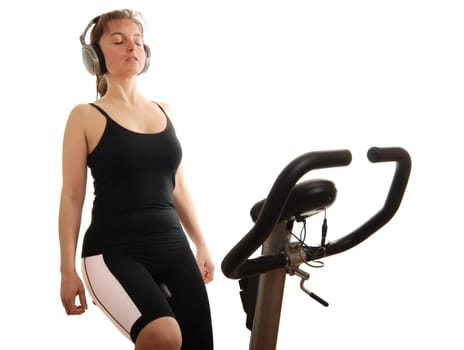 Woman with headphones listening music on spinning bicycle