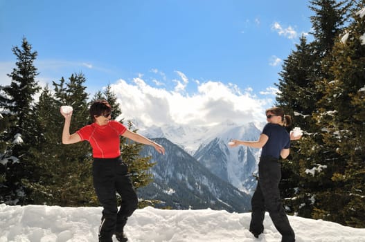 Senior woman throws snowball on her daughter - winter mature people series