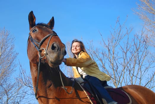 Young woman riding on big brown horse