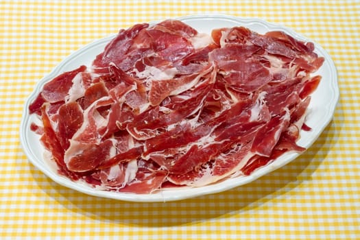 jamon serrano, spanish serrano ham presented on a plate on tablecloth