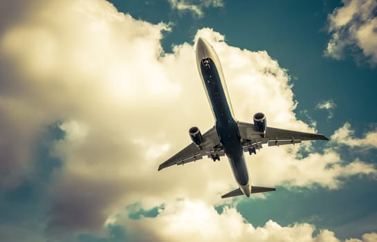 retro toned passenger jet on landing approach through a cloudy sky