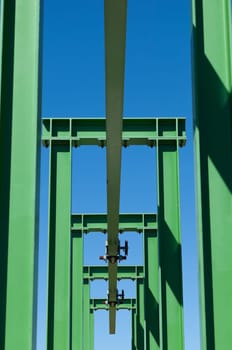 Detail of a small gantry crane painted green against the blue sky
