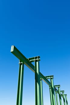 Detail of a small gantry crane painted green against the blue sky