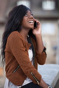 Outdoor of a portrait happy young black  teenage girl using a mobile phone