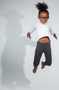 Portrait of cute Young African American girl jumping, over gray background
