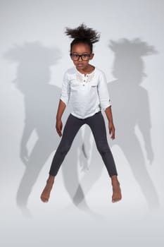 Portrait of cute Young African American girl jumping, over gray background