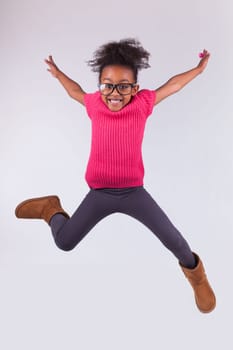 Portrait of cute Young African American girl jumping, over gray background