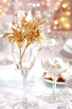 Golden branch on Christmas table. Place setting in white and golden tone.