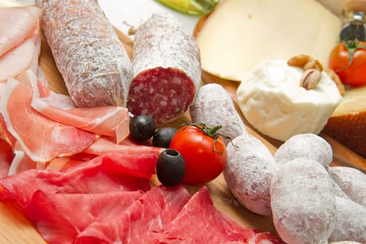 composition of cold cuts  on wooden board with different type of cheese