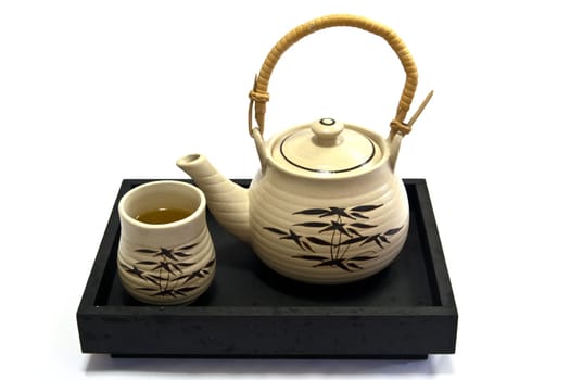 Teapot and teacup painting bamboo leaves on a black tray.