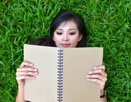 Woman lying on grass with a book