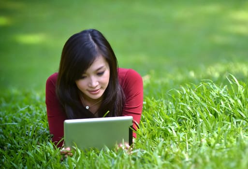 pretty woman using tablet outdoor laying on grass