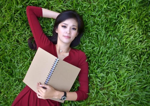 Woman lying on grass with a book