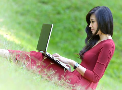 pretty  woman with laptop on green grass at the garden