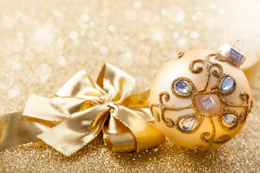 Christmas ornament with ribbon in golden tone with glittering background