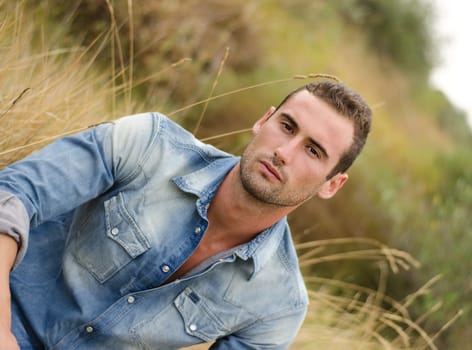 Good looking male model in jeans in a field