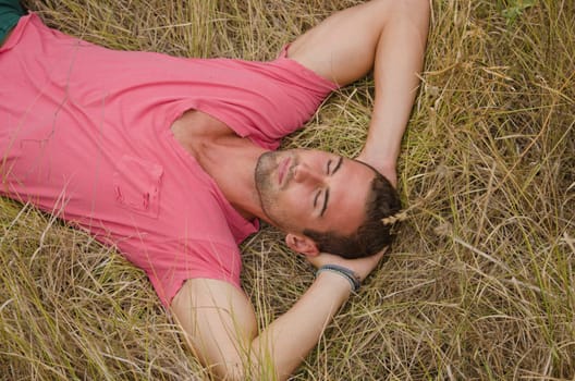 Good looking, fit male model relaxing or sleeping in a field