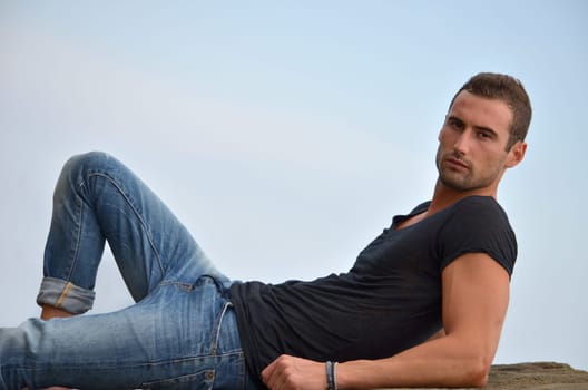 Attractive and athletic young man laying on a rock