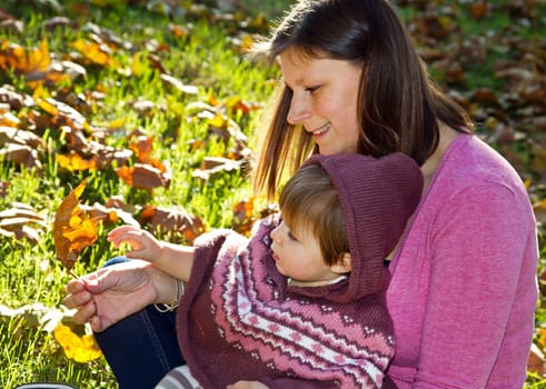 Family portrait cute little girl and happy mother. Autumn in the park.