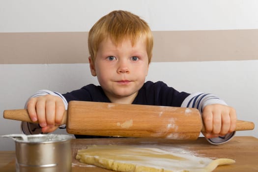 Child rolls out dough with a rolling pin