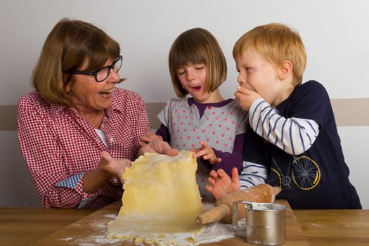 Grandma and her grandchildren roll out dough