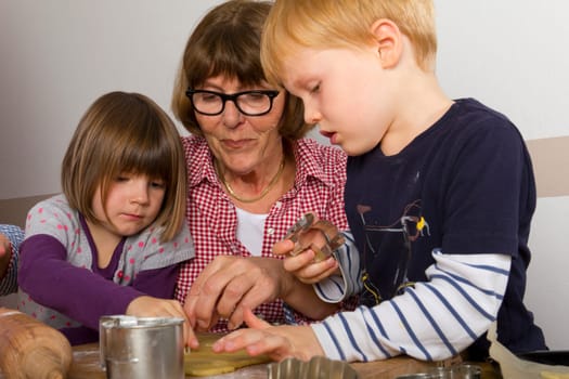 Grandma and her grandchildren cut out cookies