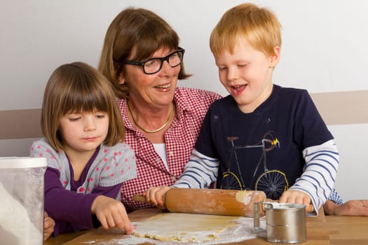 Grandma and her grandchildren roll out dough