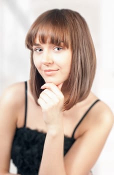 beautiful and happy young woman thinking and looking into the camera. Hand under her chin.