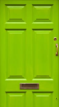 green typical residential house door in Ireland (golden lock, handle and mailbox)