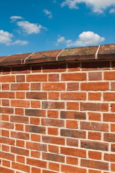 red brick wall against a gorgeous blue sky with clouds