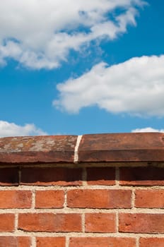 red brick wall against a gorgeous blue sky with clouds