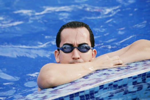 Male Swimmer resting after several laps in the indoor swimming pool
