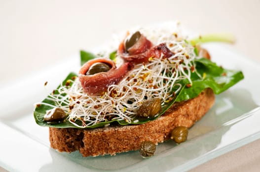Fresh sandwich with anchovies, capers, sprouts and salad