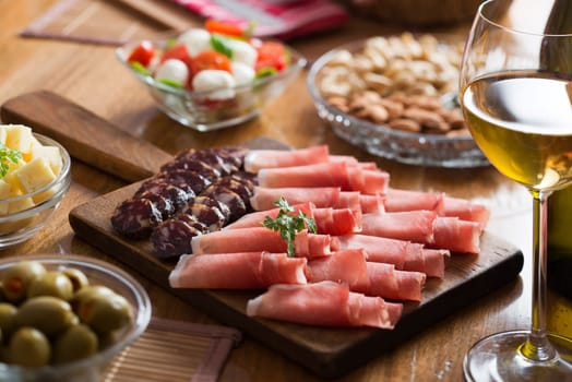 Full table of prosciutto, olives, cheese, salad and wine