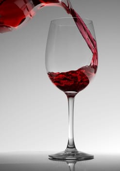 Red wine pouring into wine glass close up