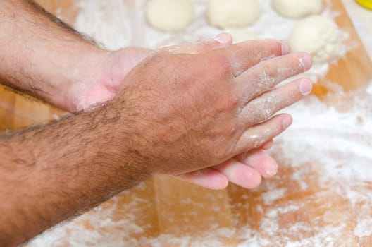 hands of the cook while preparing the pizza dough