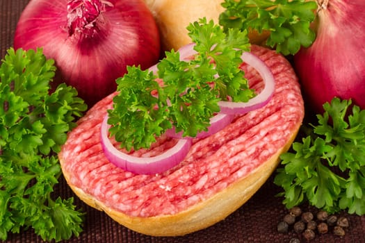 Meat rolls with parsley and onions on a bamboo mat.