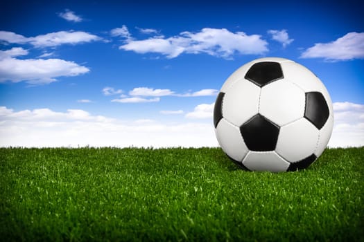 a soccerball on a green meadow in front of blue sky