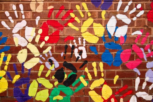 A lot of colorful hands painted to an old brickwall