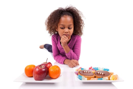 Little African Asian girl hesiatating between fruits or  candy,isolated on white background