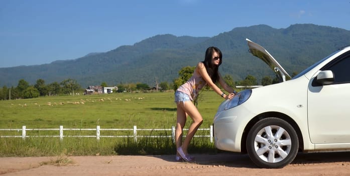 Worried young woman with her broken car