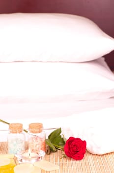 In room romantic spa concept on a hotel bed with rose and bath salt