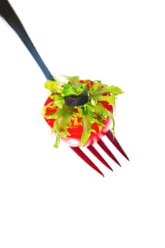 Fresh salad piled on half cherry tomato on a fork