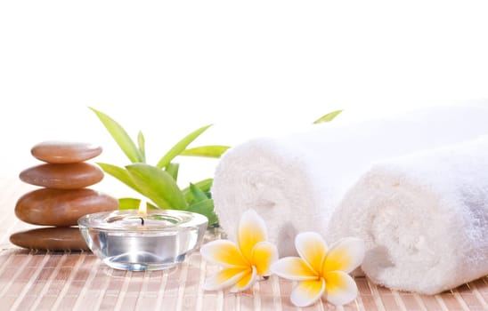 Spa concept with zen stones, flowers on bamboo mat background