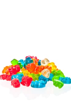 A stack of colorful gummy bears and six colorful gummy bears line up