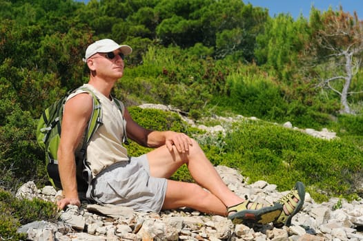 Outdoor man resting on rock after hiking, Croatia