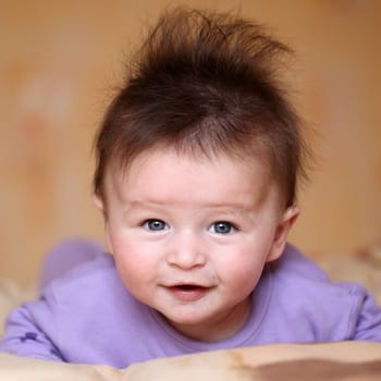 Portrait of a smiling baby 4 months old lying on his belly