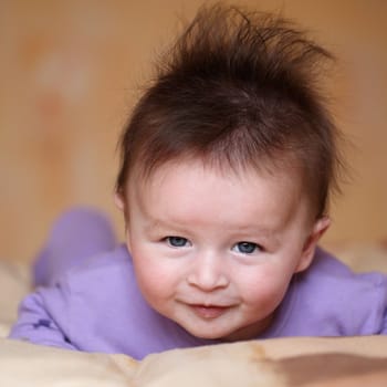 Portrait of a smiling baby 4 months old lying on his belly