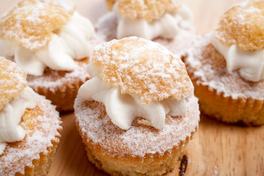 A group of fresh cakes with cream on wooden board